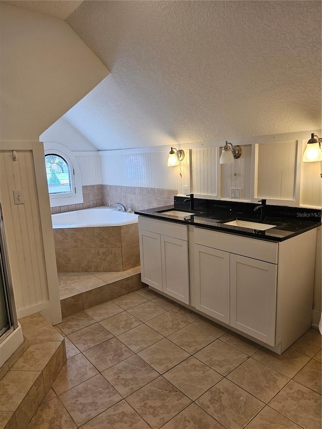 bathroom with tiled tub, tile patterned flooring, vanity, and vaulted ceiling