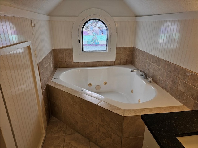 bathroom featuring tiled tub, tile patterned flooring, and lofted ceiling