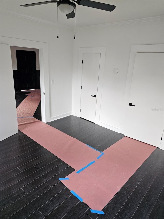 exercise area featuring ceiling fan, dark wood-type flooring, and ornamental molding