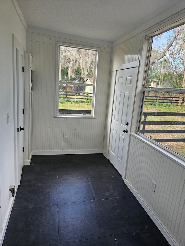 interior space featuring crown molding, plenty of natural light, and wooden walls