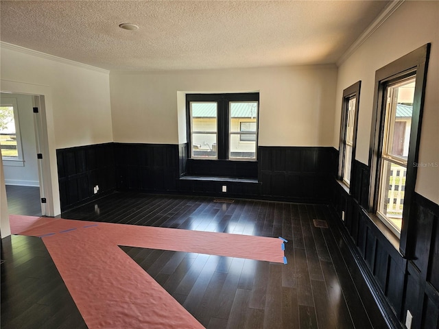 spare room featuring dark hardwood / wood-style flooring, a textured ceiling, and ornamental molding