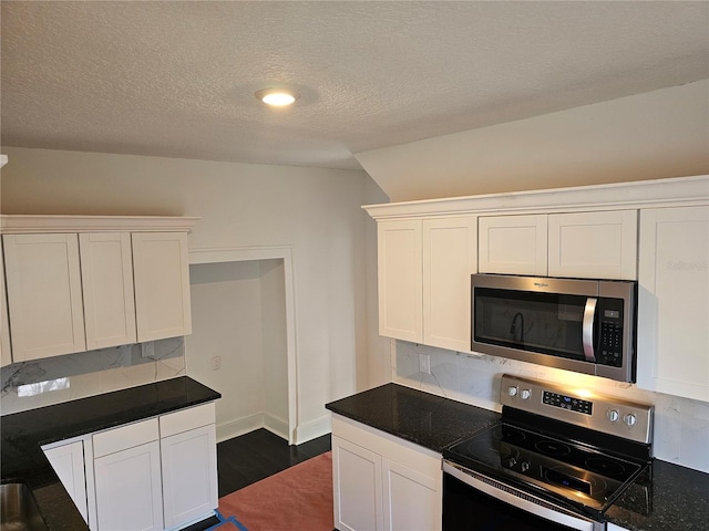 kitchen with dark stone counters, a textured ceiling, appliances with stainless steel finishes, tasteful backsplash, and white cabinetry