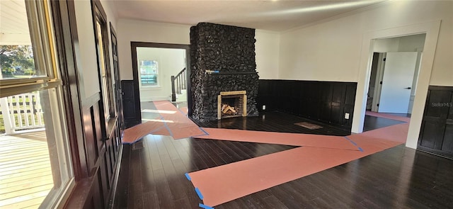 living room with wood-type flooring, ornamental molding, and a fireplace