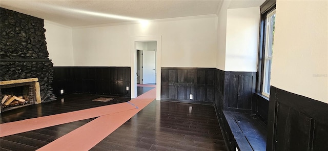 interior space with a fireplace, a textured ceiling, dark hardwood / wood-style floors, and ornamental molding