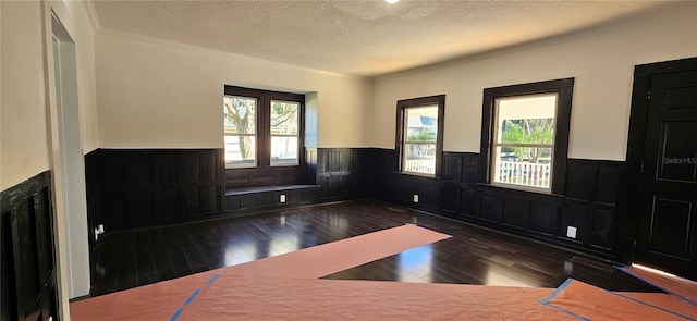 interior space with dark wood-type flooring, a textured ceiling, and ornamental molding