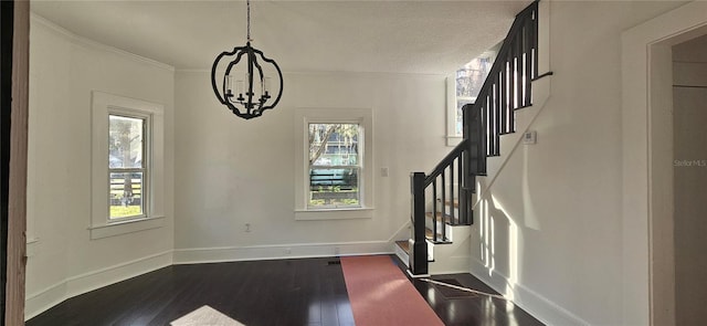 foyer entrance with a textured ceiling, dark hardwood / wood-style floors, crown molding, and an inviting chandelier