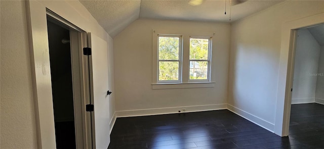 unfurnished room featuring dark hardwood / wood-style flooring, a textured ceiling, and vaulted ceiling