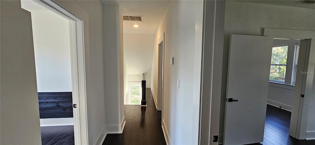 corridor with a textured ceiling and dark wood-type flooring