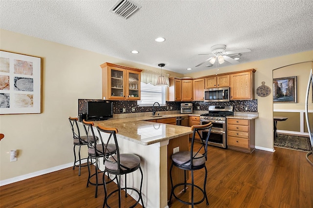 kitchen featuring appliances with stainless steel finishes, a textured ceiling, sink, decorative light fixtures, and kitchen peninsula