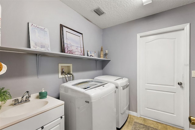 washroom with sink, washing machine and clothes dryer, cabinets, and a textured ceiling