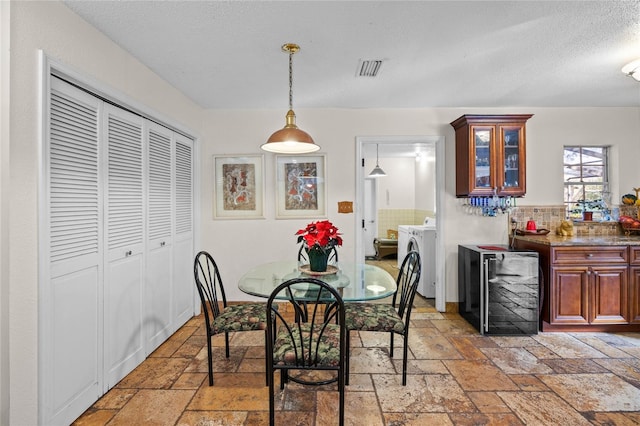 dining room with wine cooler, a textured ceiling, and washer / dryer