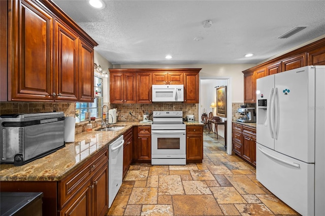 kitchen featuring light stone countertops, white appliances, tasteful backsplash, and sink