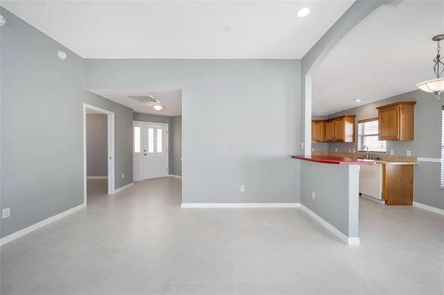 kitchen featuring white dishwasher, sink, pendant lighting, and kitchen peninsula