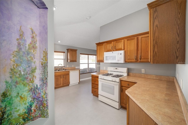 kitchen with sink, white appliances, and vaulted ceiling