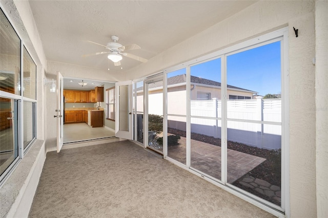 unfurnished sunroom with ceiling fan