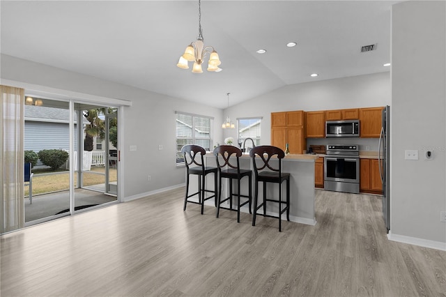 kitchen with stainless steel appliances, a center island, an inviting chandelier, and decorative light fixtures