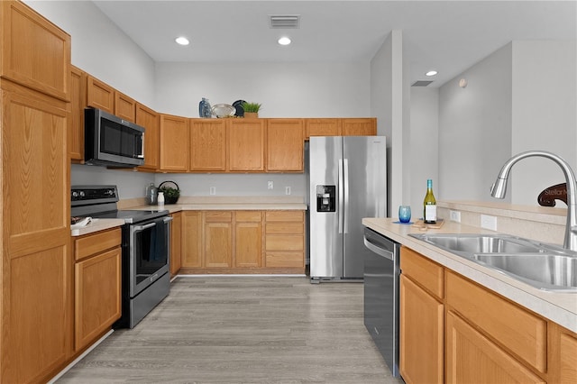 kitchen featuring appliances with stainless steel finishes, sink, and light wood-type flooring