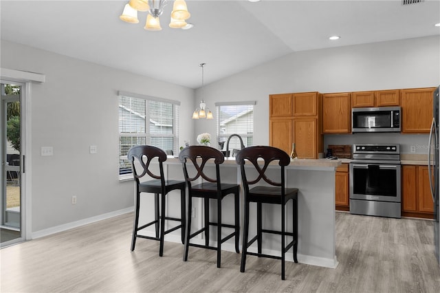 kitchen with a breakfast bar, appliances with stainless steel finishes, hanging light fixtures, a chandelier, and light wood-type flooring