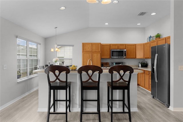 kitchen featuring appliances with stainless steel finishes, a breakfast bar area, a kitchen island with sink, and hanging light fixtures