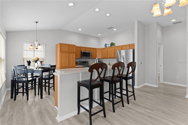 kitchen featuring stainless steel appliances, light hardwood / wood-style floors, a chandelier, and decorative light fixtures