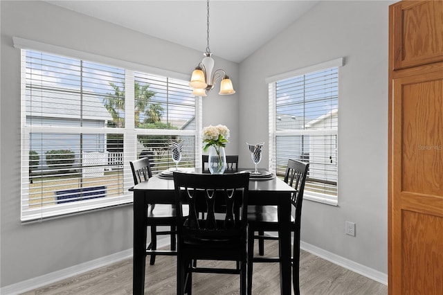 dining area featuring lofted ceiling, a notable chandelier, and light wood-type flooring