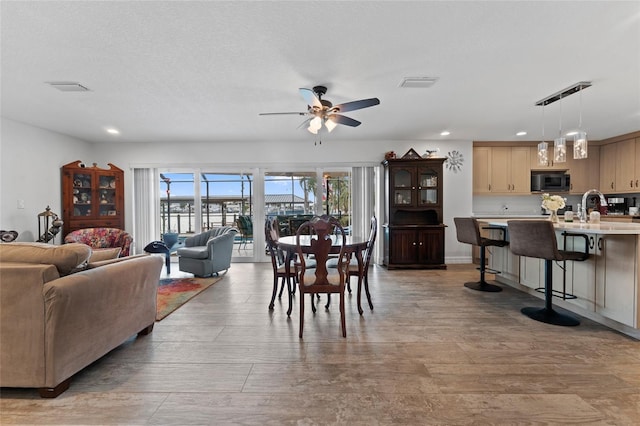 dining room featuring ceiling fan, light wood-type flooring, and sink