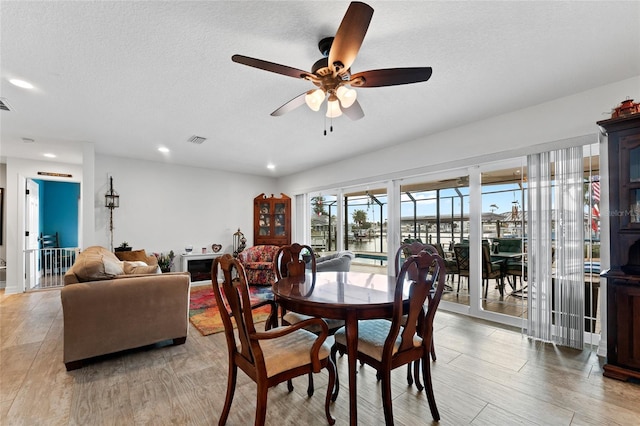 dining area featuring ceiling fan, light hardwood / wood-style floors, and a textured ceiling