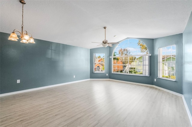 spare room with hardwood / wood-style floors, ceiling fan with notable chandelier, a textured ceiling, and vaulted ceiling