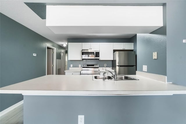 kitchen featuring kitchen peninsula, white cabinetry, sink, and appliances with stainless steel finishes