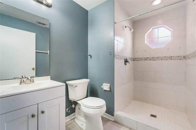 bathroom featuring hardwood / wood-style flooring, vanity, toilet, and tiled shower