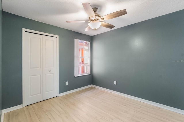 unfurnished bedroom featuring ceiling fan, a closet, a textured ceiling, and light hardwood / wood-style flooring