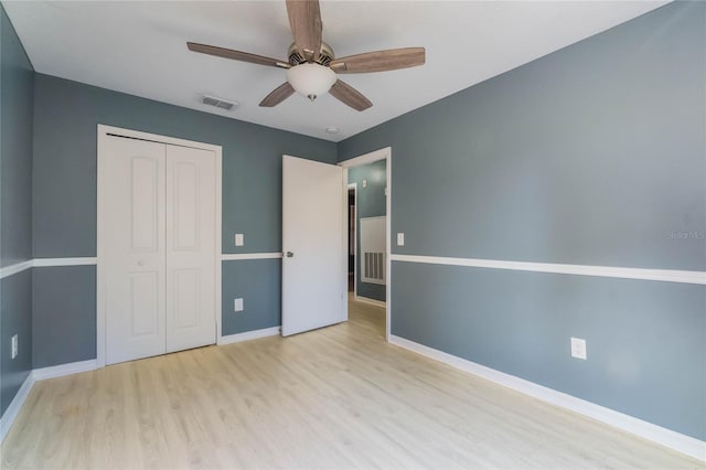 unfurnished bedroom with ceiling fan, light wood-type flooring, and a closet