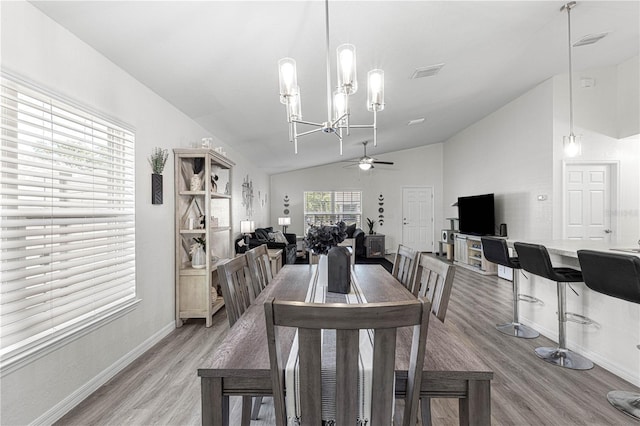 dining area featuring ceiling fan with notable chandelier, light hardwood / wood-style floors, and lofted ceiling