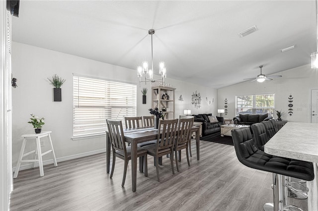 dining room featuring hardwood / wood-style floors, ceiling fan with notable chandelier, and vaulted ceiling