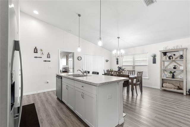 kitchen featuring a kitchen island with sink, dark wood-type flooring, sink, hanging light fixtures, and stainless steel appliances