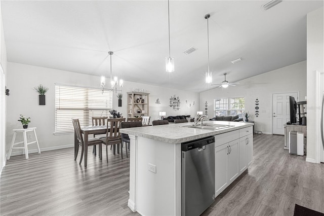 kitchen featuring stainless steel dishwasher, vaulted ceiling, sink, a center island with sink, and white cabinetry