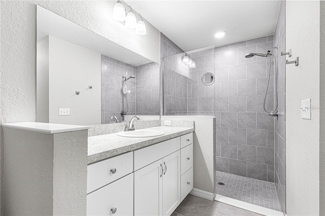 bathroom with tile patterned flooring, a tile shower, vanity, and a textured ceiling