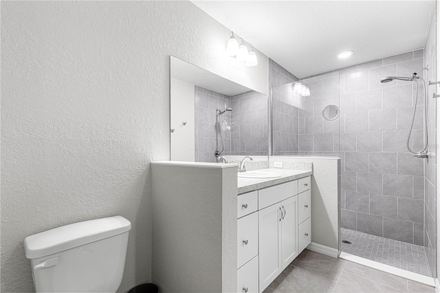 bathroom featuring tile patterned floors, vanity, toilet, and tiled shower