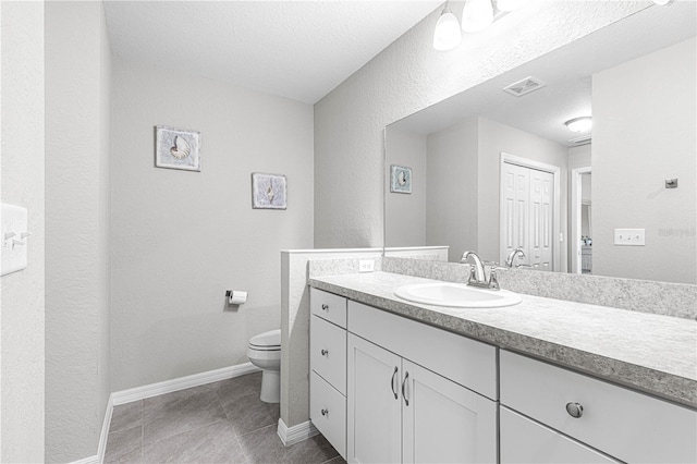 bathroom featuring vanity, toilet, and a textured ceiling