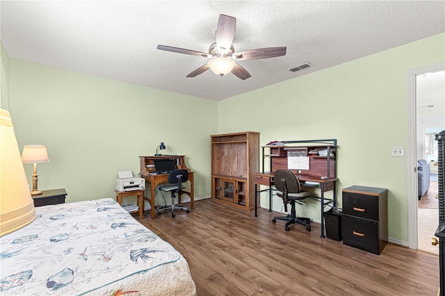 bedroom with hardwood / wood-style floors, a textured ceiling, and ceiling fan