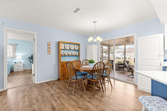 dining area featuring a chandelier, a textured ceiling, and light hardwood / wood-style floors