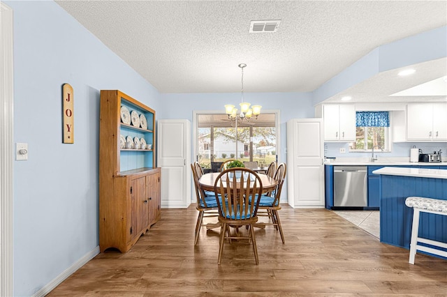 dining area featuring a chandelier, a textured ceiling, and light hardwood / wood-style flooring