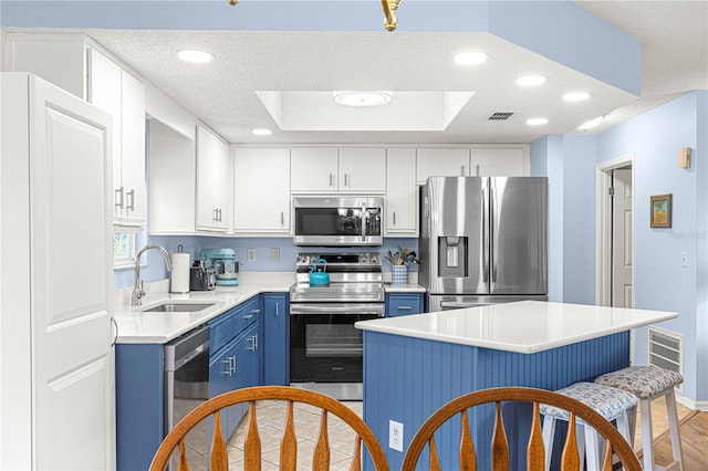 kitchen featuring stainless steel appliances, a kitchen island, sink, blue cabinetry, and white cabinetry