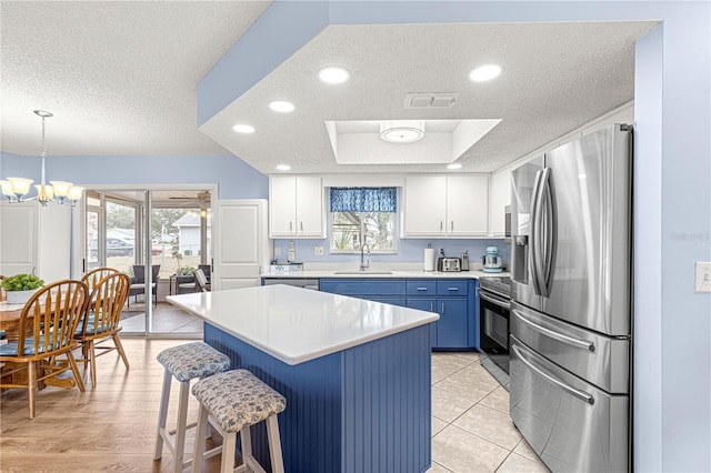 kitchen with stainless steel fridge, sink, blue cabinetry, range, and white cabinetry