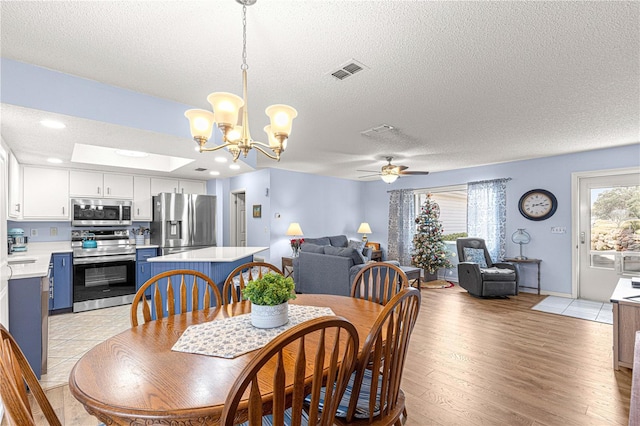 dining room featuring ceiling fan with notable chandelier, sink, a textured ceiling, and light hardwood / wood-style flooring