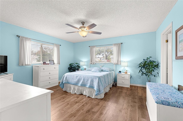 bedroom featuring multiple windows, light wood-type flooring, a textured ceiling, and ceiling fan