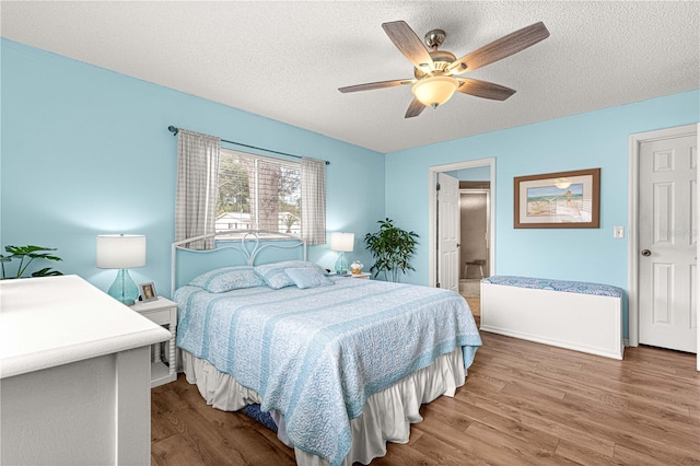 bedroom with hardwood / wood-style floors, a textured ceiling, ceiling fan, and connected bathroom