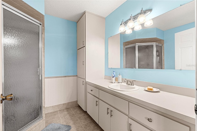 bathroom with tile patterned flooring, vanity, a shower with door, and a textured ceiling