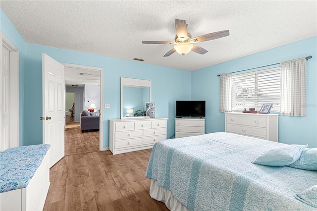 bedroom featuring a textured ceiling, light hardwood / wood-style flooring, and ceiling fan