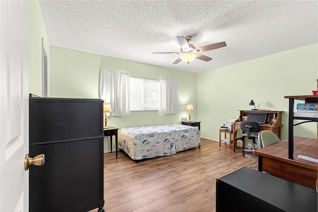 bedroom featuring a textured ceiling, light wood-type flooring, and ceiling fan